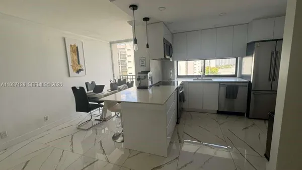 a kitchen with stainless steel appliances kitchen island granite countertop a sink and a refrigerator