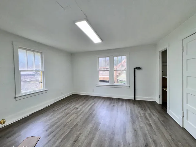 an empty room with wooden floor and windows