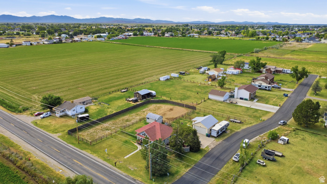 5264 West 5500th Street South Hooper, UT 84315 - Photo 36 of 38 Aerial perspective showcasing multiple residential properties, expansive green fields, and a distant mountain range
