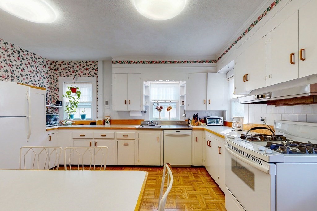 246 Clark Road Brookline, MA 02445 - Photo 7 of 18 a kitchen with white cabinets a sink dishwasher and white appliances