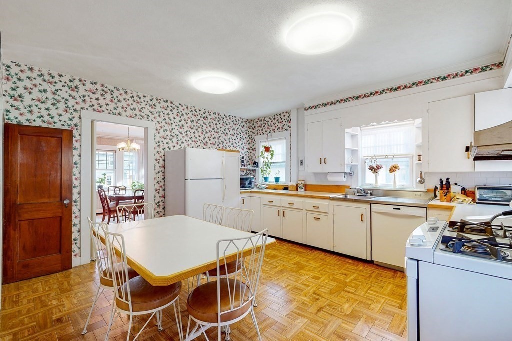 246 Clark Road Brookline, MA 02445 - Photo 8 of 18 a kitchen with a dining table chairs refrigerator and cabinets