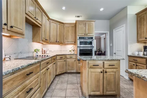 a kitchen with kitchen island granite countertop a sink counter top space appliances and cabinets