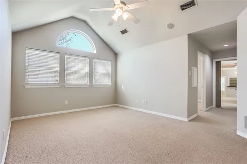 an empty room with chandelier fan and windows