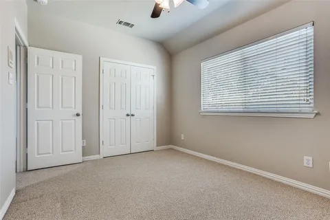 an empty room with chandelier fan and windows