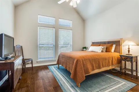 a bedroom with a bed a flat screen tv and dresser next to a window