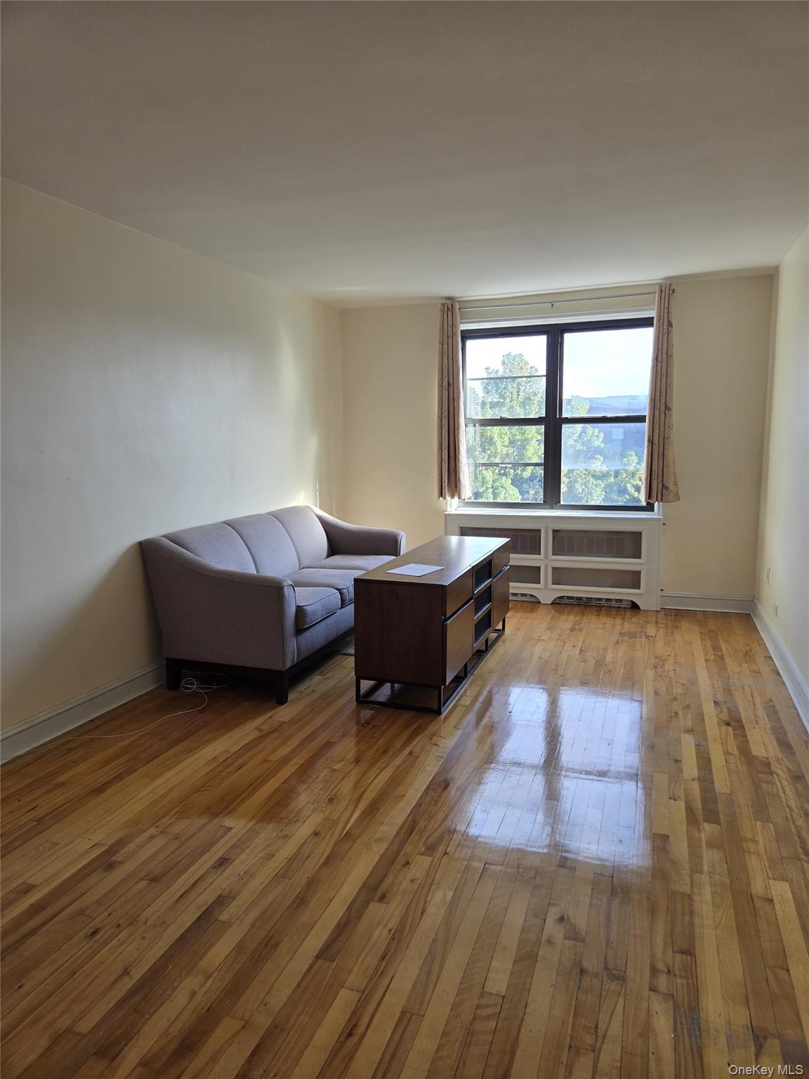 87-09 34th Avenue, Unit 6K Queens, NY 11372 - Photo 6 of 12 a living room with furniture and a large window