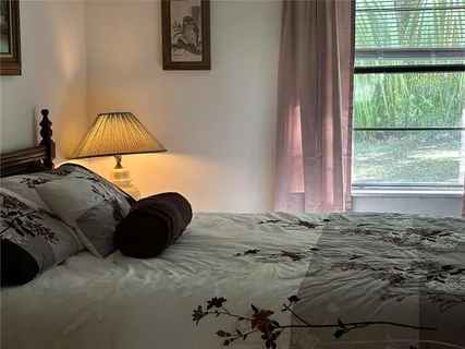 a bedroom with a bed and a large mirror next to a window