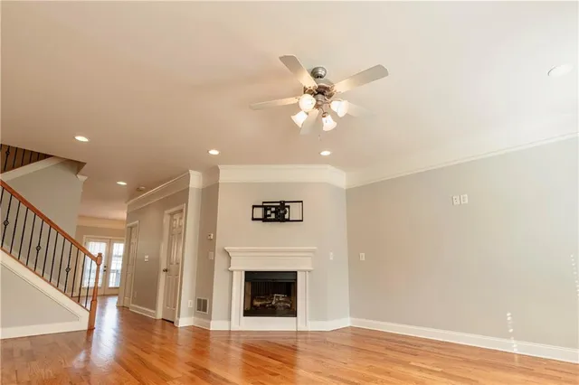 a view of an empty room with wooden floor and a fireplace