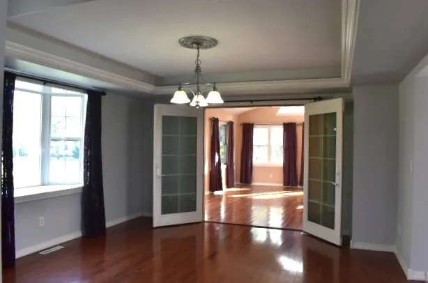 a view of a room with wooden floor chandelier and windows
