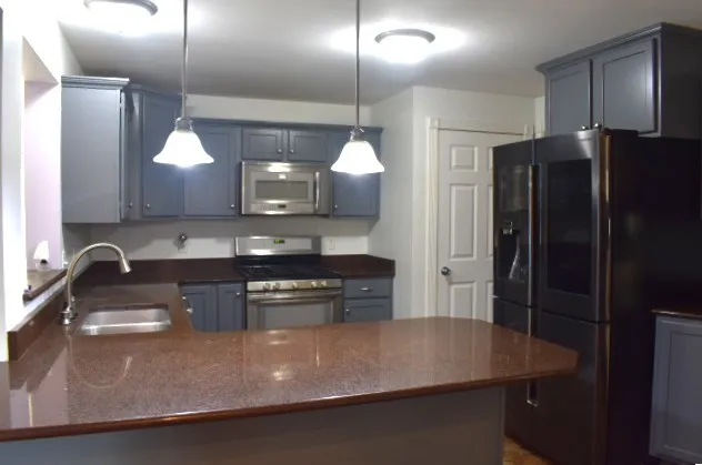 a kitchen with stainless steel appliances granite countertop a sink a stove and a refrigerator