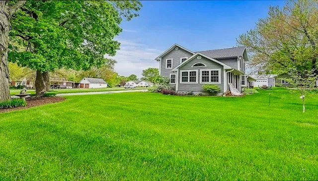 a view of a house with a big yard and large trees