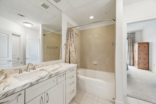 a bathroom with a granite countertop sink a mirror a bathtub and shower
