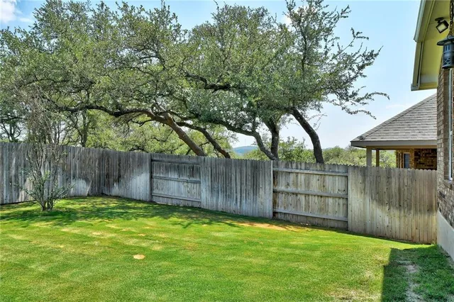 a view of a backyard with a large tree and wooden fence