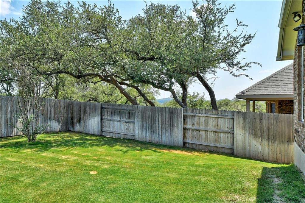 416 Peakside Circle Dripping Springs, TX 78620 - Photo 30 of 31 a view of a backyard with a large tree and wooden fence