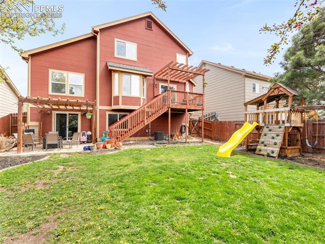 5346 Gentle Wind Road Colorado Springs, CO 80922 - Photo 27 of 28 Back of house featuring a fenced backyard, a pergola, a playground, and a patio area