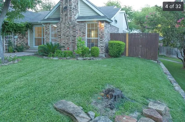 a view of a brick house with a yard and plants