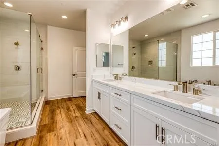 a spacious bathroom with a double vanity sink a large mirror and shower