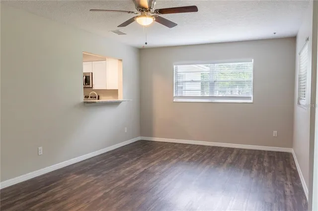 an empty room with wooden floor fan and windows