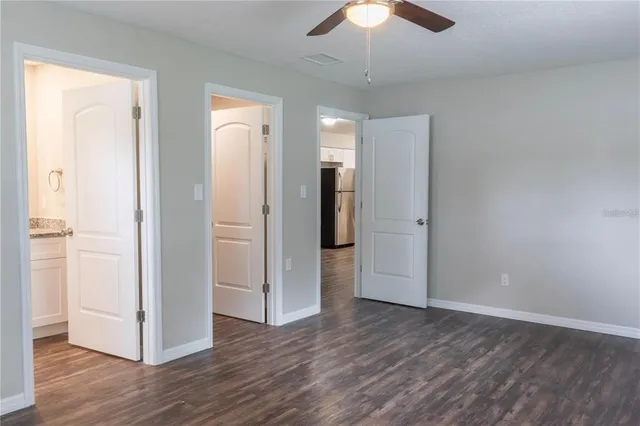 an empty room with wooden floor a ceiling fan and entryway