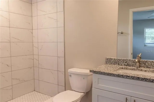 a bathroom with a granite countertop toilet and sink