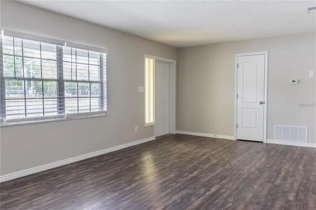 a view of an empty room with wooden floor and a window