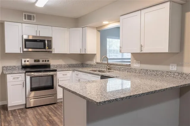 a kitchen with granite countertop a stove microwave and sink