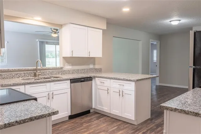 a kitchen with granite countertop a sink stove and cabinets