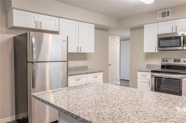 a kitchen with granite countertop a refrigerator stove top oven and sink
