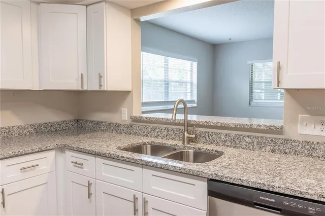 a kitchen with granite countertop white cabinets and a sink