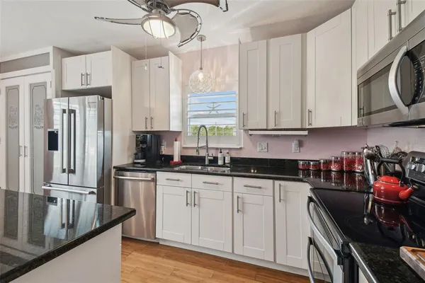 a kitchen with granite countertop a sink a counter space appliances and cabinets