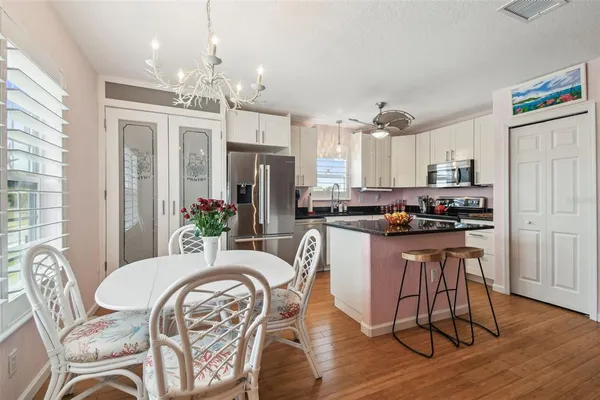 a kitchen with stainless steel appliances granite countertop a dining table chairs a refrigerator and microwave