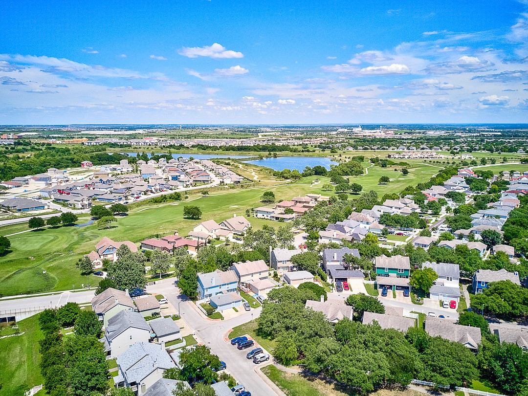 311 A Utterback Kyle, TX 78640 - Photo 39 of 40 Aerial perspective showcasing a residential community with varied architectural styles, a central lake, and surrounding golf course greens