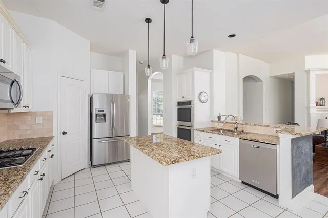 a kitchen with granite countertop a sink a stove a dining table and chairs