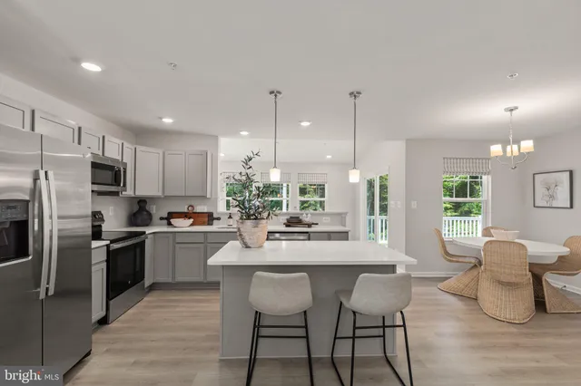 a kitchen with stainless steel appliances kitchen island granite countertop a stove top oven a sink dishwasher a dining table and chairs with wooden floor