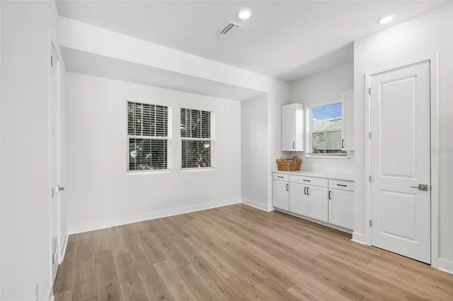 a kitchen with white cabinets and wooden floor