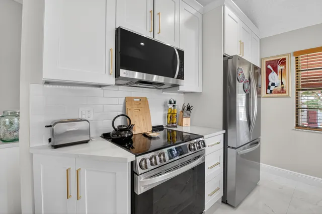 a kitchen with stainless steel appliances a sink a stove and a refrigerator with white cabinets