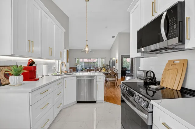 a kitchen with stainless steel appliances a stove a sink dishwasher and white cabinets with wooden floor