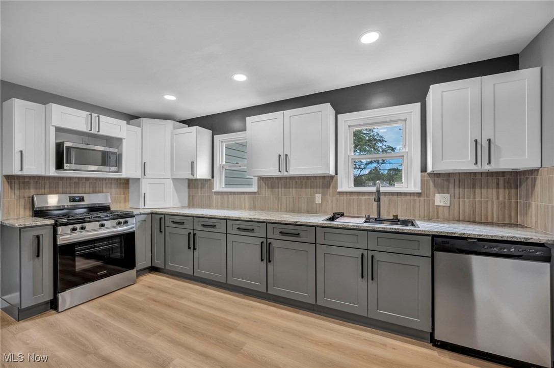 20202 Sumpter Road Cleveland, OH 44128 - Photo 12 of 46 Kitchen with gray cabinets, appliances with stainless steel finishes, backsplash, white cabinets, and light wood finished floors