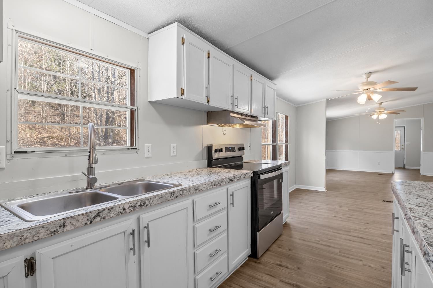 624 Nickletown Road Sugar Tree, TN 38380 - Photo 16 of 45 a kitchen with granite countertop a sink stainless steel appliances white cabinets and wooden floor
