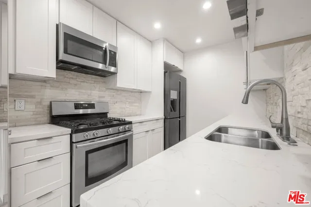 a kitchen with stainless steel appliances kitchen island a stove a sink and a microwave