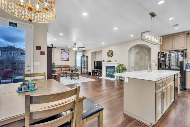 a view of living room with kitchen island stainless steel appliances furniture a fireplace and a chandelier