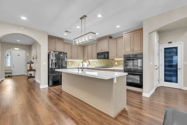 a large kitchen with stainless steel appliances kitchen island a large counter top and a refrigerator