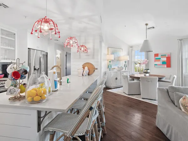 a view of a dining room and kitchen with furniture a chandelier and wooden floor
