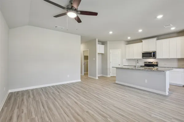 a view of kitchen with granite countertop cabinets and refrigerator