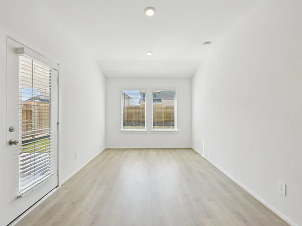 a view of an empty room with a window and wooden floor