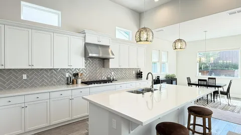 a kitchen with stainless steel appliances granite countertop a sink a stove a dining table and chairs