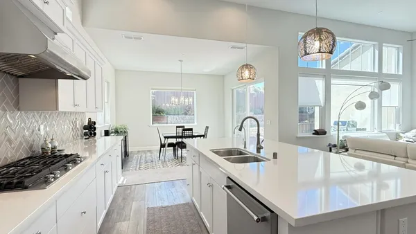 a large kitchen with granite countertop a sink a stove top oven a clock and cabinets