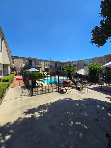 a view of a patio with dining table and chairs under an umbrella with palm trees