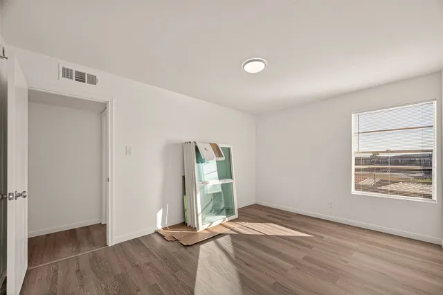 an empty room with wooden floor and windows