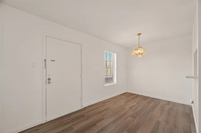an empty room with wooden floor and window